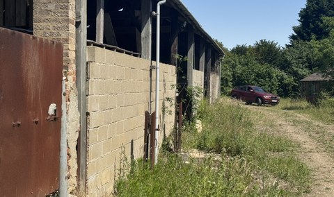 Traditional timber-framed agricultural barn with brick and blockwork infill panels and a corrugated roof, viewed along its open side elevation